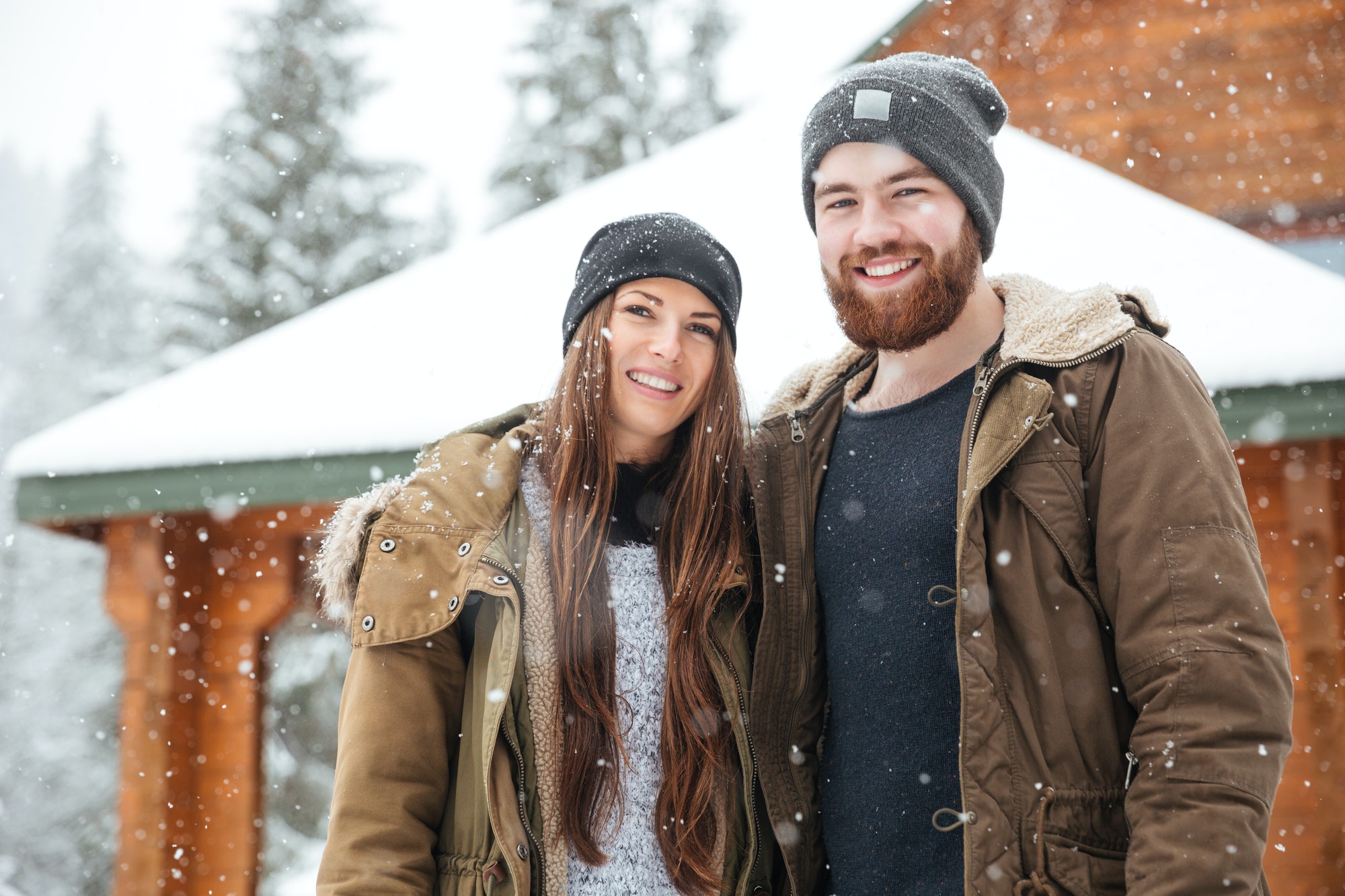 Couple standing in front of log cabine at winter